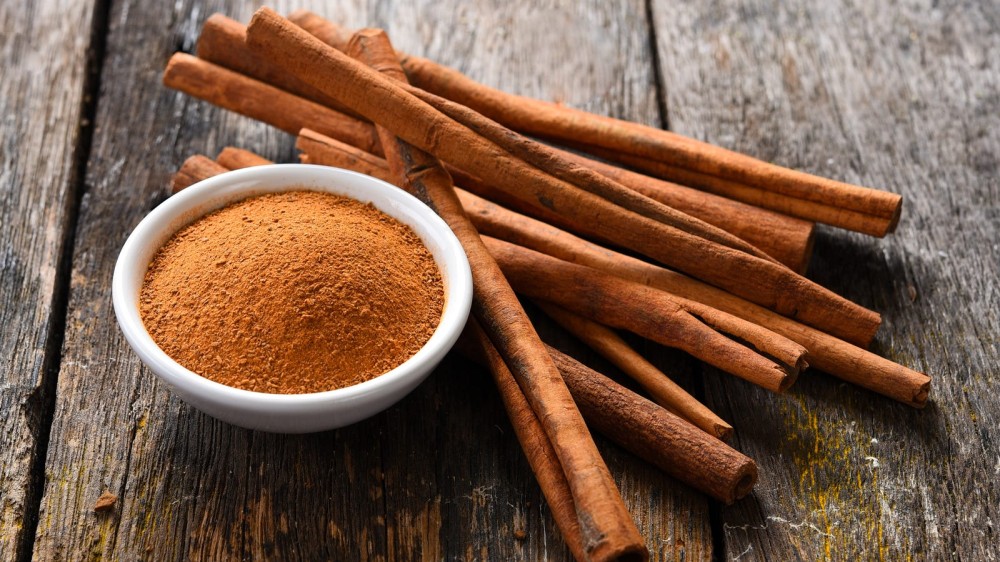 a bunch of cinnamon sticks with a little bowl of ground cinnamon.