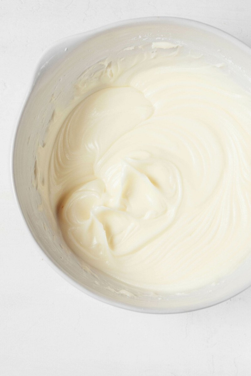 An image of a white bowl, which is filled with freshly beaten vegan cream cheese frosting.